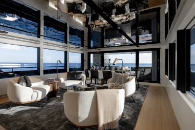 A modern and luxurious living room with large windows offering a stunning view of the ocean in the background.