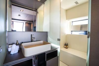 A modern bathroom with a vessel sink in the foreground and a window with natural light in the background.