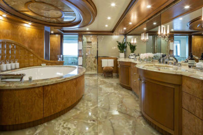 A luxurious bathroom with a large oval bathtub in the foreground and a double vanity with mirrors and ornate lighting in the background.