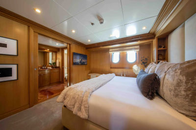 A luxurious bedroom with a plush bed in the foreground and a glimpse into an en-suite bathroom through an open doorway in the background.