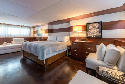A luxurious bedroom with a large bed and plush seating in the foreground is set against a backdrop of striped walls and ambient lighting.