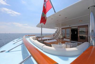 A luxurious yacht's deck with plush seating in the foreground and the calm ocean stretching to the horizon in the background.