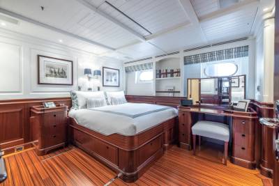 A luxurious bedroom with a large bed in the foreground and a vanity table and bookshelves in the background.