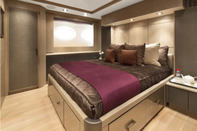 A luxurious bedroom with a large bed in the foreground and a window with oval panes in the background.