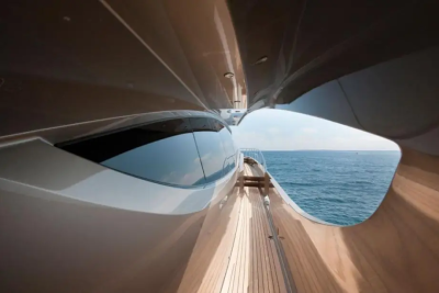 A sleek, modern yacht's interior curves frame a view of the calm blue ocean and sky.