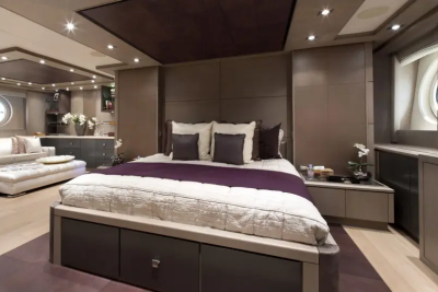 A luxurious bedroom with a large bed in the foreground and a seating area with a sofa and ottoman in the background.