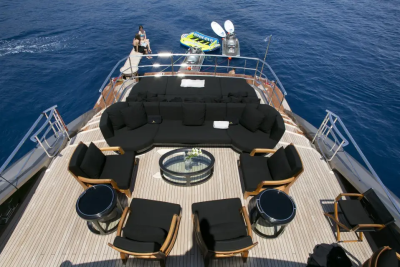 A luxurious yacht deck with plush seating in the foreground and the calm blue ocean in the background.