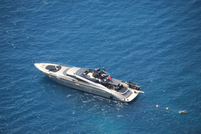 A sleek white yacht floats on the deep blue ocean, with a small dinghy tethered nearby.
