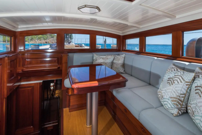 A polished wooden table and plush seating fill the foreground, while the background reveals a serene ocean view through the yacht's windows.