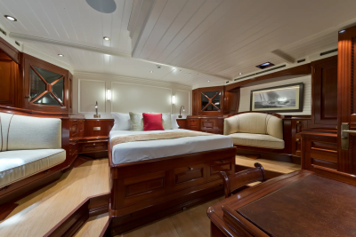A luxurious yacht cabin features a plush bed in the foreground and a framed seascape on the wall in the background.