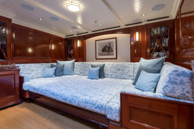 A large, patterned daybed with blue pillows dominates the foreground, while the background features dark wood paneling, cabinetry, and a framed picture.