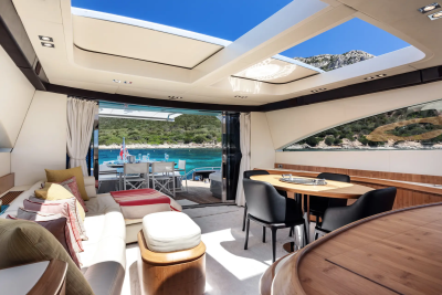 A luxurious yacht interior with a comfortable seating area in the foreground and a scenic ocean view with islands in the background.