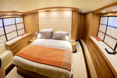 A luxurious bedroom with a large bed in the foreground and wooden paneling and windows in the background.