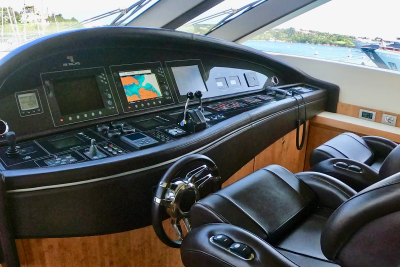 A luxurious yacht's helm, with plush leather seats in the foreground and a digital navigation display visible through the windows in the background.