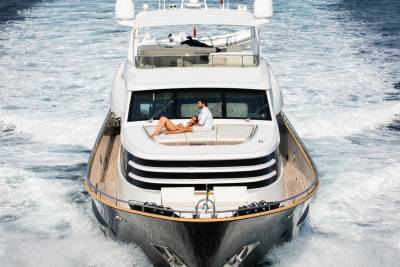 A couple relaxes on the deck of a luxurious yacht as it cuts through the choppy blue ocean.