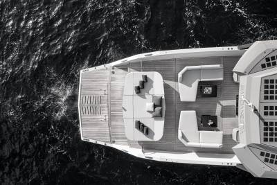 A luxurious yacht with plush seating and sunbeds rests on dark, rippling water.