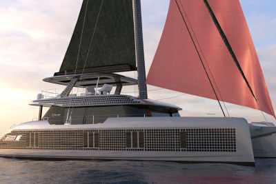 A modern white catamaran with dark and pink sails glides on calm water under a soft sky.