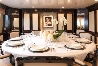 A formal dining table set for a meal is centered in a luxurious room with a portrait of Marilyn Monroe hanging on the back wall.