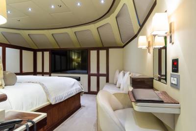 A luxurious bedroom with a large bed in the foreground and a television and seating area in the background.