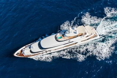 A luxurious white yacht cruises through deep blue ocean water, leaving a foamy wake behind it.