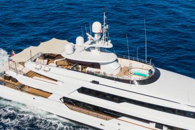 A luxurious white yacht with a jacuzzi on its upper deck cruises through the deep blue ocean.