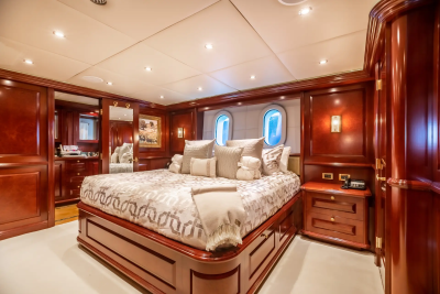 A luxurious bedroom with a large bed in the foreground and oval windows in the background.
