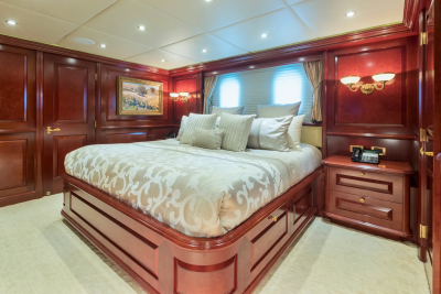 A luxurious bedroom with a large bed in the foreground and ornate wooden paneling and windows in the background.