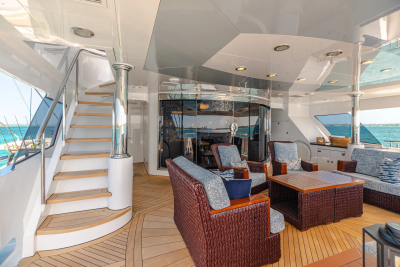 A luxurious yacht deck with comfortable seating in the foreground and a clear blue ocean in the background.