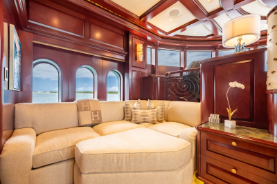 A plush sectional sofa with decorative pillows sits in the foreground, while arched windows reveal a calm ocean and sky in the background.