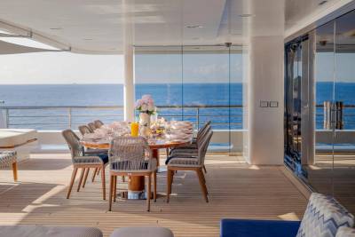 A beautifully set dining table on a yacht's deck overlooks a calm blue ocean.