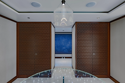 A modern hallway with a glass railing in the foreground and a large blue abstract painting in the background.