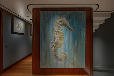 A large seahorse painting on a wooden panel dominates the foreground, while a hallway with wooden floors and framed artwork recedes into the background.