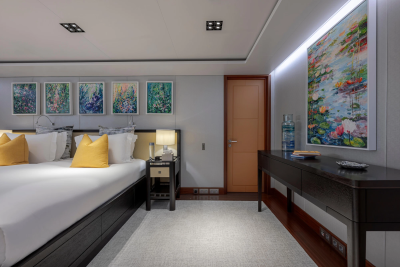 A luxurious bedroom with a large bed in the foreground and a hallway with artwork in the background.