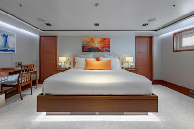 A luxurious bedroom with a large bed in the foreground and a desk and artwork on the walls in the background.