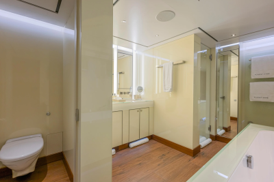 A modern bathroom with a toilet in the foreground and a vanity and shower in the background.
