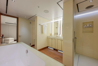 A spacious, modern bathroom with a large bathtub in the foreground and a vanity with a mirror and a shower stall in the background.