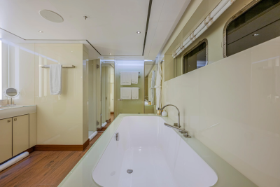 A spacious, modern bathroom with a large bathtub in the foreground and a glass-enclosed shower and vanity in the background.