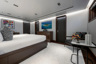 A luxurious bedroom with a large bed in the foreground and a television displaying a tropical island scene in the background.