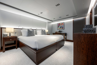 A luxurious bedroom with a large bed in the foreground and a desk with artwork in the background.
