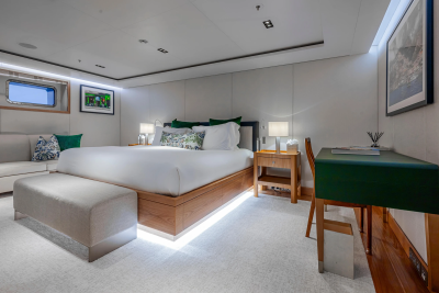 A luxurious bedroom with a large bed in the foreground and a desk and window in the background.