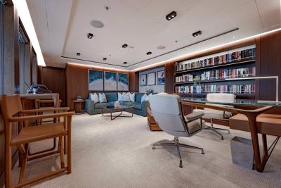 A luxurious office space with a plush seating area in the foreground and a wall of bookshelves in the background.