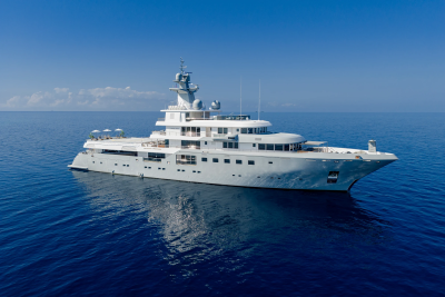 A large, white luxury yacht floats on calm, deep blue water under a clear, bright sky.