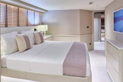 A luxurious bedroom with a neatly made bed in the foreground and a modern dresser with a television in the background.