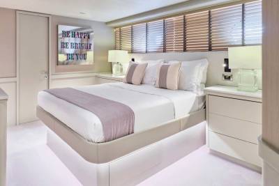 A luxurious bedroom with a plush bed in the foreground and blinds covering the windows in the background.