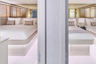 Two beds with white linens are visible in the foreground, while the background features mirrored walls and blinds.