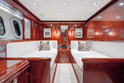 Two twin beds with tiger-print pillows are in the foreground, while the background features wood-paneled walls with framed pictures and oval windows.