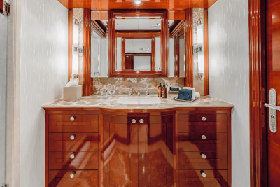A luxurious wooden vanity with a marble countertop and a large mirror is centered in the foreground, while the background features textured walls and subtle lighting.