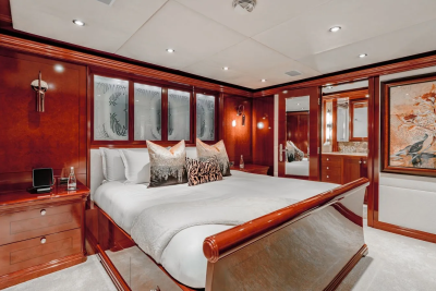 A luxurious bedroom with a large bed in the foreground and a mirrored closet and bathroom entrance in the background.