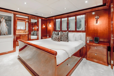 A luxurious bedroom with a large bed in the foreground and a vanity area with mirrors in the background.