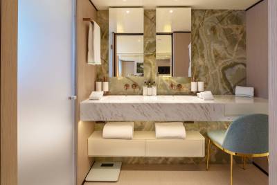 A modern bathroom vanity with a marble countertop and dual sinks is in the foreground, while a wall with green marble and mirrors forms the background.